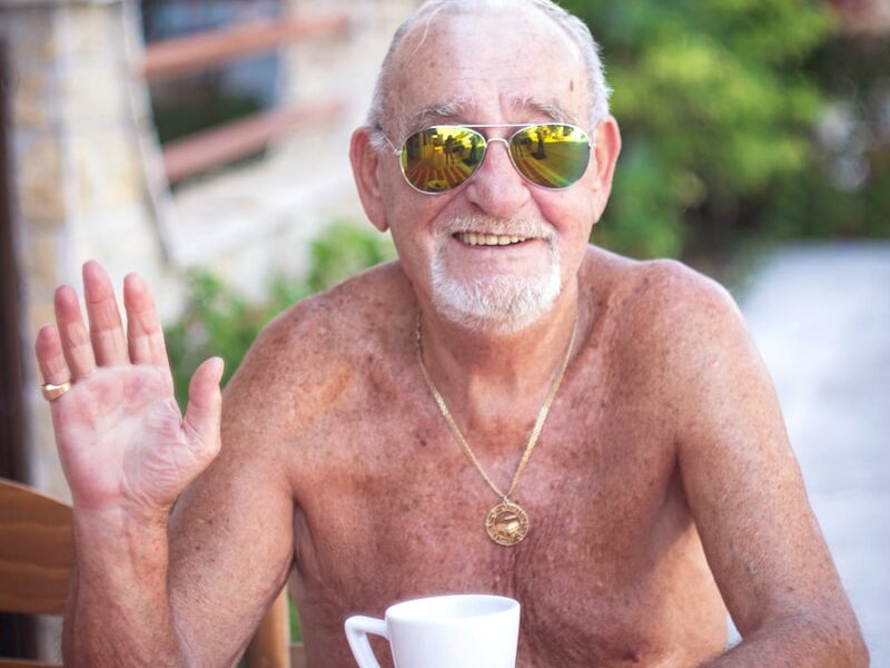 topless man wearing sunglasses sitting on chair